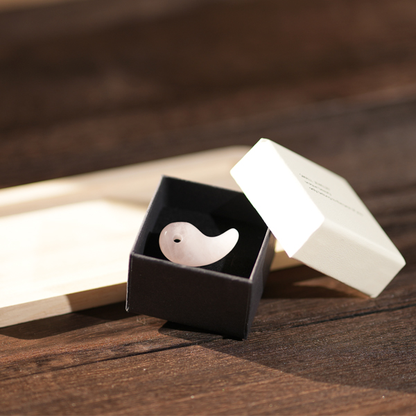 商品撮影によるピンクのアクセサリーの静物ビジュアル。木製テーブルの上に置かれたボックスを用いた、落ち着いた質感の演出